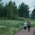 Senior couple jogging on a scenic park path surrounded by greenery.